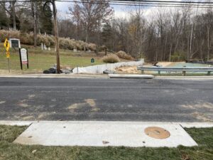 Photo of storm drain along Baltimore Road with the Rockville Cemetery and restored stream in the background at the road crossing of the culvert.