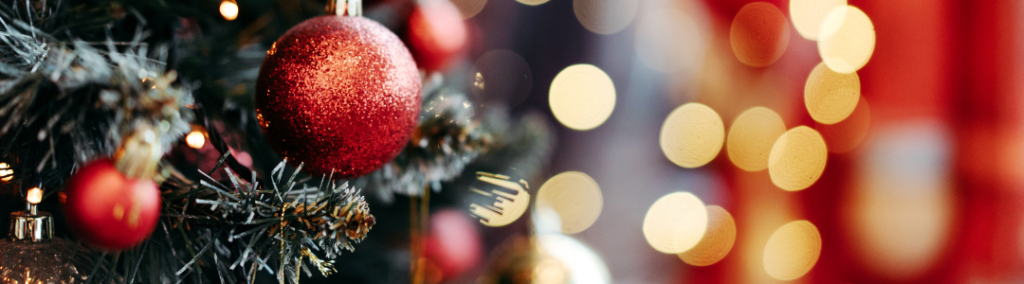 Christmas tree with red ornaments and twinkling lights in the background