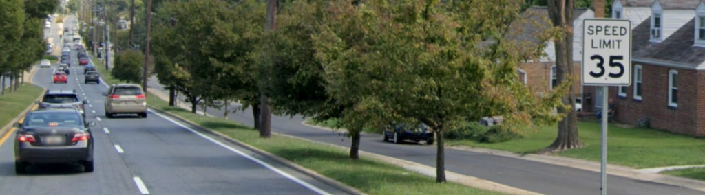 Image depicts vehicles traveling down Veirs Mill Road, with a speed limit sign in a median to the right.