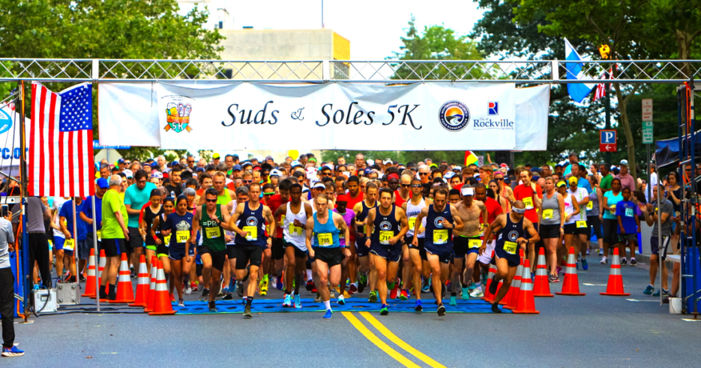 Image depicts runners at the start line for the Suds and Soles 5K