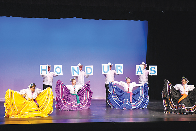 Dancers on a stage holding signs that spell out Honduras