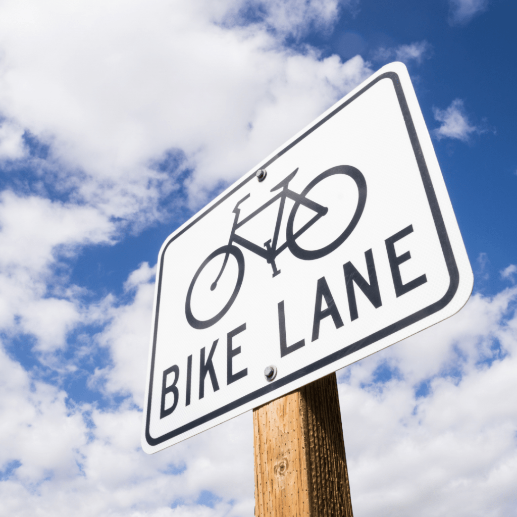 Bike Lane sign on a wooden signpost with clouds and a blue sky in the background