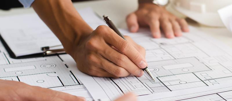 A closeup of a man drawing architectural plans