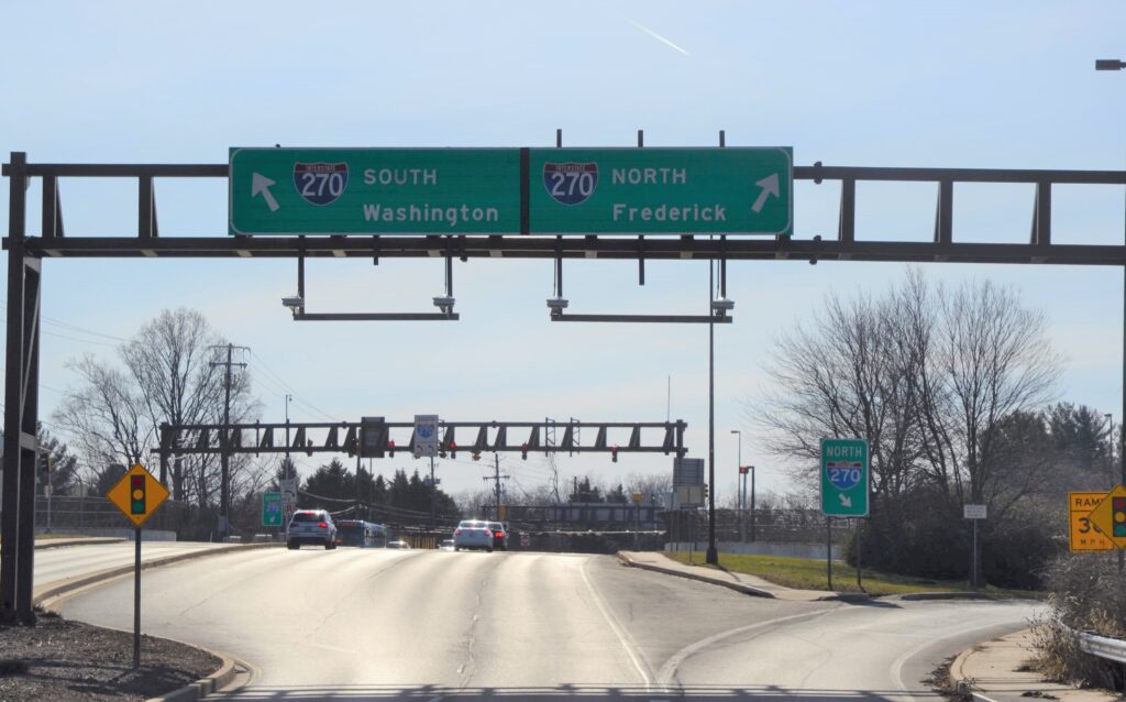 Overhead green highway signs over interchange of Interstate 270 at Falls Road in Rockville, Maryland, with arrows and wording directing traffic to I-270 south to Washington and I-270 North to Frederick.